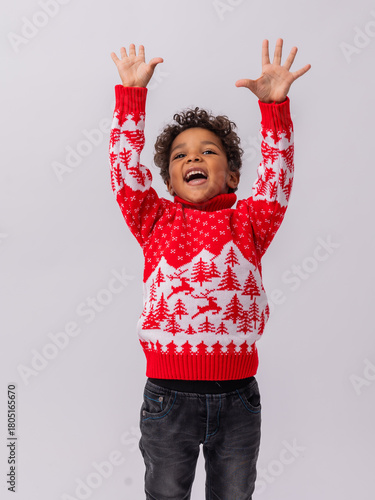 Fotografie little mulatto boy in a New Year's sweater on a white background in a studio