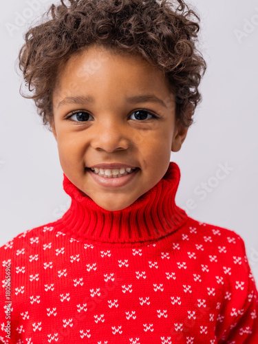 Obraz na płótnie little mulatto boy in a New Year's sweater on a white background in a studio