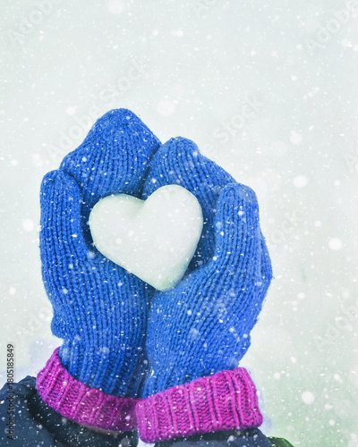 Hands in knitted mittens with heart of snow in winter day. Love concept. Valentine day background.	