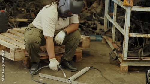 Industrial used car concept of 4k Resolution. African American female mechanic welds scrap metal in an old auto parts factory.
