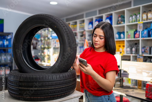 Woman standing in an auto parts store researching car tires on her smartphone