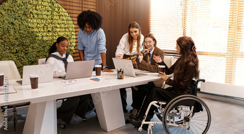 Inclusive diverse business team working together, woman in wheelchair at office meeting