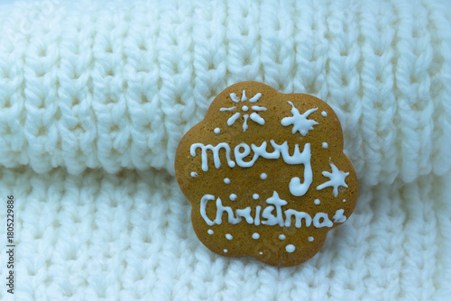 Gingerbread cookie decorated with royal icing on white knitted background. Merry Christmas