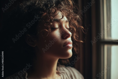 Woman With Curly Hair in Soft Light Reflecting by the Window