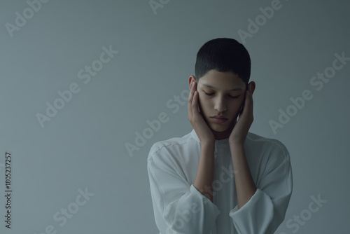teenager gently compressing their head with both hands embodying serene and peaceful moment
