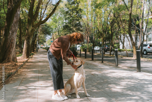 A woman is walking her dog along a tree-lined path in Mexico City’s Polanco neighborhood