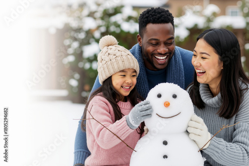 Happy multi ethnic family building snowman together in snowy winter outdoor. Winter holiday activities and family bonding lifestyle banner with copy space