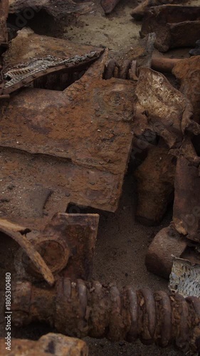 rusted tank tracks and scrap piled in derelict scrapyard, close-up reveal of corroded sprockets, bolts, and track links covered in flaking patina and grime, heavy textures and muted brown
