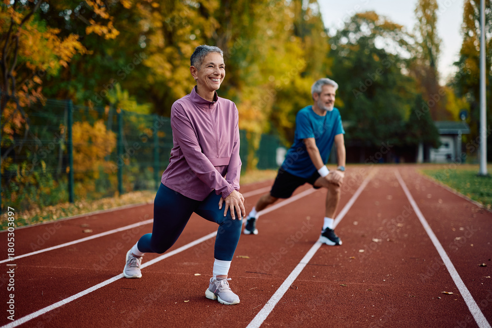 Obraz premium Mature athletes stretching their legs while warming up for sports training outdoors.