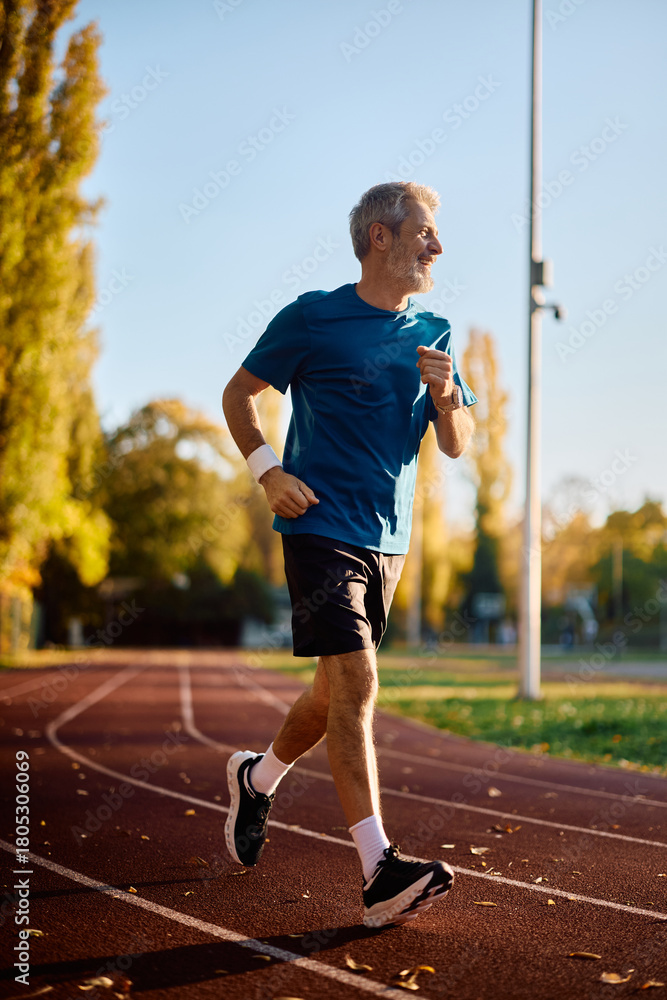 Naklejka premium Full length of mature sportsman jogging in park.