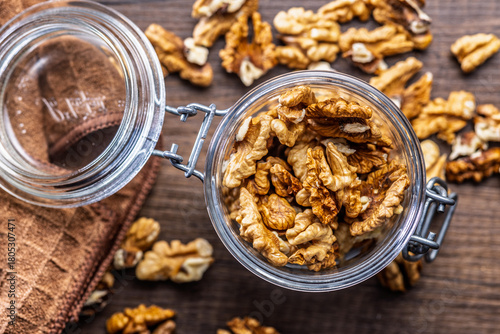 Peeled walnut kernels in jar on wooden table. Top view.