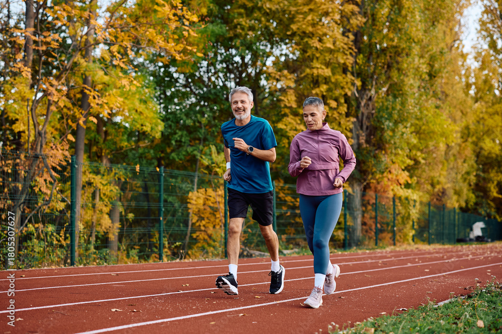 Obraz premium Mature sports couple running during outdoor workout in autumn.