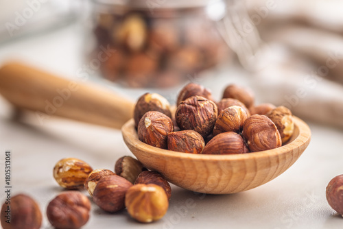 Peeled hazelnut kernels on wooden spoon on kitchen table.