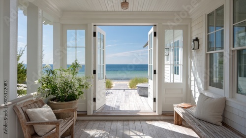 A white house with a porch overlooking the ocean. The porch has a bench and two chairs, and a potted plant. The view of the ocean is breathtaking and serene