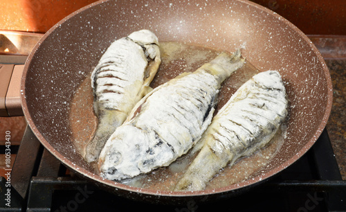 cooking freshwater fish crucian carp in a frying pan. the fish is dipped in flour and fried in vegetable sunflower oil. fish meat has a sweetish taste