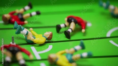Fallen foosball players on the table soccer field. Close-up of tabletop sport. Symbol of defeat and halted gameplay. Concept of losing team. Failure, frustration, game interruption.