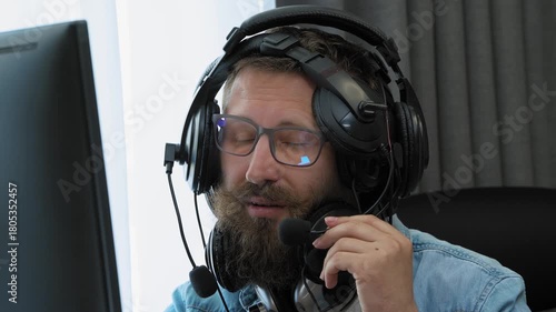 Сallcenter worker consulting clients at home, wearing multiple wired headsets. Overworked and exhausted man. Professional burnout, stress, multitasking. Home office setting, remote work concept.