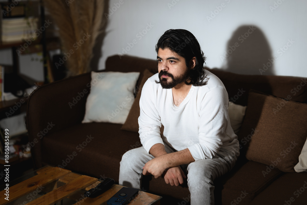 Obraz premium Man Watching TV with Remote Control in Dramatic Light
