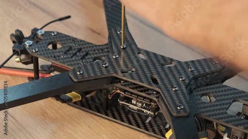 use a tool to precisely tighten the final bolt, securing the motor arm mounts onto the FPV drone frame. ssembly, finalizing the crucial framework for the FPV quadcopter.