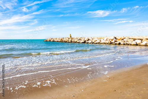 Fototapeta Naklejka Na Ścianę i Meble -  Gentle waves washing the sandy beach under a bright blue sky near Peschici, Apulia, Italy