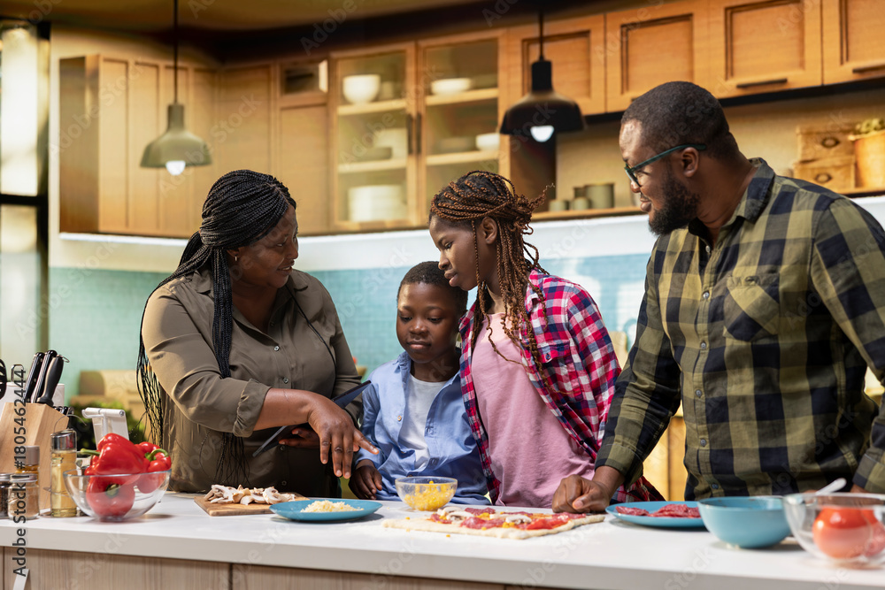 Fototapeta premium Parents teaching young kids how to make family recipe homemade pizza in the kitchen, explaining steps with ingredients to learn to cook efficiently. Making food in their cozy home.