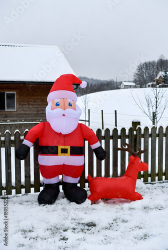 Inflatable Santa and reindeer Christmas decorations in snowy yard
