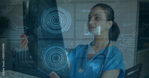 Holding radiograph female clinician in blue scrubs with stethoscope studying AR overlays in clinic