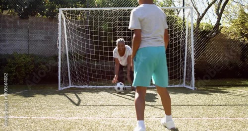 Child shooting at goal in practice, sports streaks tracing ball while keeper saving child scoring
