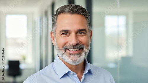 Smiling middle-aged man with gray beard and blue shirt happy