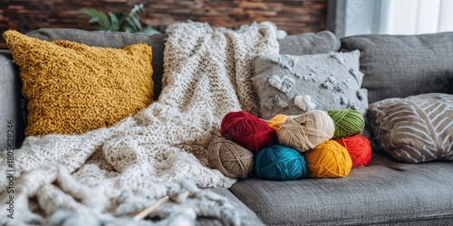 Cozy living room scene with pillows, a blanket, and colorful yarn balls on a grey couch