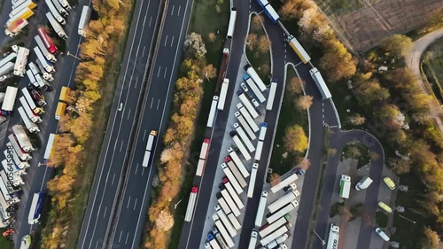 moving trucks on busy road, aerial perspective of bustling highway with parked and moving trucks, overhead view capturing congested highway active with freight trucks and roadside facilities