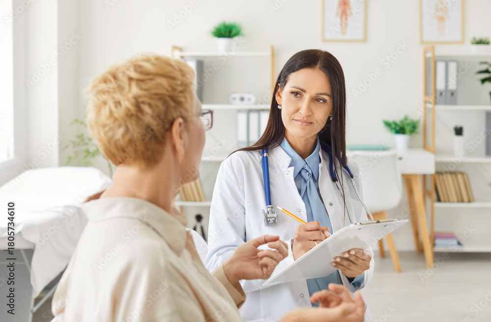 Obraz premium Attentive female doctor or nurse provides medical consultation to a woman patient during an appointment at the hospital, offering healthcare aid and conducting a professional exam.