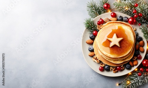 Stack of homemade pancakes with fresh berries, nuts, and star butter, served on a christmas decorated plate