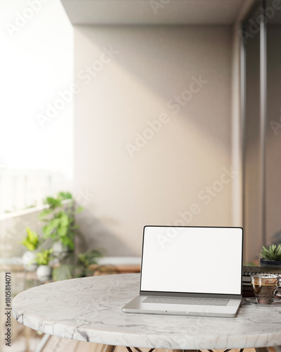 Blank screen laptop with coffee cup and plant on round marble table at balcony terrace with sunlight