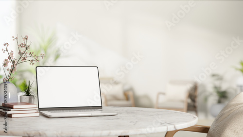 Fototapeta Naklejka Na Ścianę i Meble -  White screen laptop with book and sakura cherry blossom flower vase on round marble table and armchair.