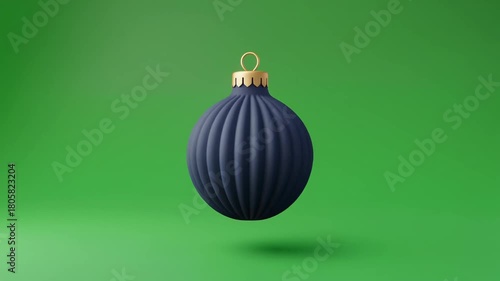A solitary navy blue Christmas ornament, suspended against a vibrant green backdrop, evokes holiday joy and festive cheer with its classic design.