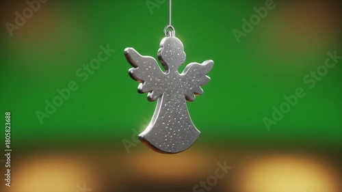 A shimmering silver angel Christmas ornament hangs gracefully against a blurred green backdrop, evoking festive holiday cheer and seasonal decorations.