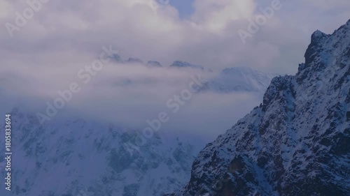 A view of the snowy mountains in the North Caucasus region of Russia, partially obscured by clouds.