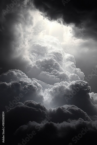 Towering billowing storm clouds parting to reveal a shaft of light, dramatic monochrome sky evoking awe and ominous hope