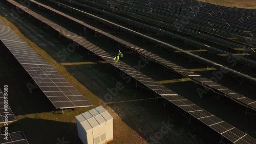 Workers inspect solar panels at large renewable energy site in sunny afternoon