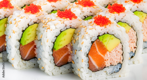 Macro shot of neatly arranged sushi rolls (California Roll) filled with salmon, avocado, and creamy mix, topped with tobiko and sesame for vibrant presentation.