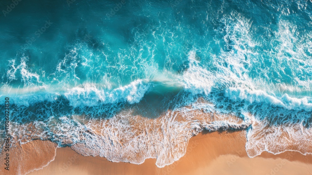 Obraz premium Crystal clear waters roll onto a golden sandy beach, creating beautiful waves under the bright sun. The tranquility of the scene invites relaxation and enjoyment.