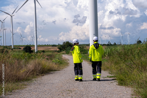 Workers inspecting wind turbines in a renewable energy field on a sunny day
