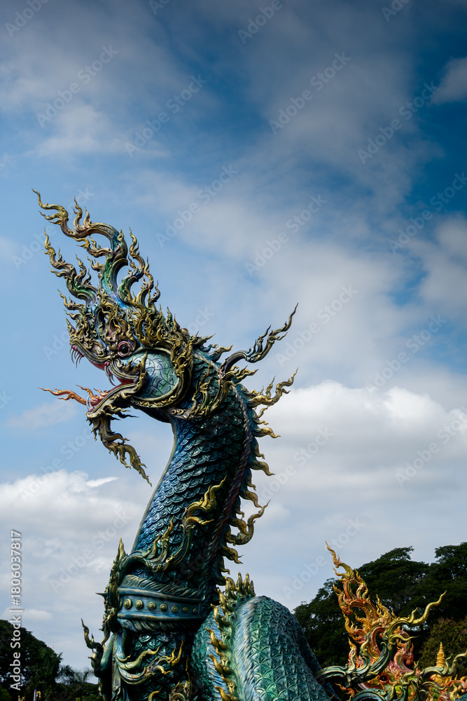 Fototapeta premium Phra That Phanom stupa with golden Buddha statues and vibrant naga serpents, showcasing ornate Thai architecture, sacred temple art, and spiritual heritage under a bright blue sky