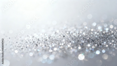 A shimmering abstract background featuring a gradient of soft white to sparkling silver glitter creating a festive and elegant visual effect.