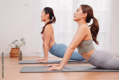 Wallpaper Mural Two Asian women practicing yoga cobra pose together on mats. indoor space, flexibility, healthy lifestyle, relaxation, and body alignment through stretching exercise. Torontodigital.ca