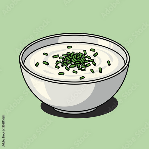 A white bowl filled with creamy dip or sour cream, garnished with fresh green chopped chives on a light green background.