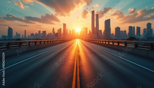 Empty highway leads to cityscape at sunset. Sun shines brightly on road between tall modern skyscrapers. Sky glows with orange, yellow clouds. City skyline expands under warm evening light. Journey