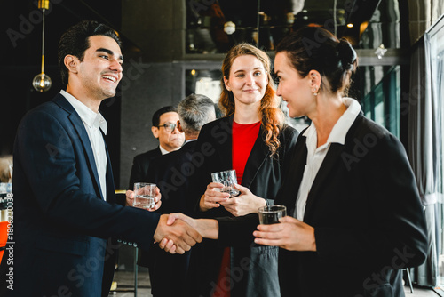 Business professionals greet each other with a handshake while networking at a corporate event, capturing a moment of connection, professionalism, and partnership in a formal setting.