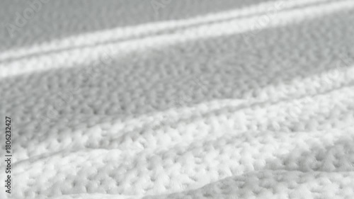 Soft white mattress texture with morning sunlight. Quilted fabric pattern and cozy bedroom atmosphere.